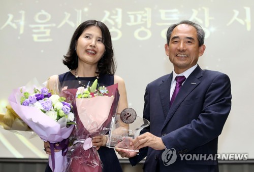 '미투운동' 확산에 기여한 공로로 서울시 성평등상 대상 수상자로 선정된 최영미 시인이 3일 오후 서울시청에서 열린 시상식에서 윤준병 서울시 행정1부시장으로부터 상패를 받은 뒤 기념촬영하고 있다. 2018.7.3 / 연합뉴스