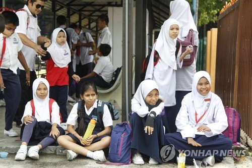 2018년 7월 2일 말레이시아 쿠알라룸푸르 외곽의 한 학교 앞에서 초등학생들이 부모를 기다리고 있다. [AP=연합뉴스 자료사진] 기사와 관련 없음