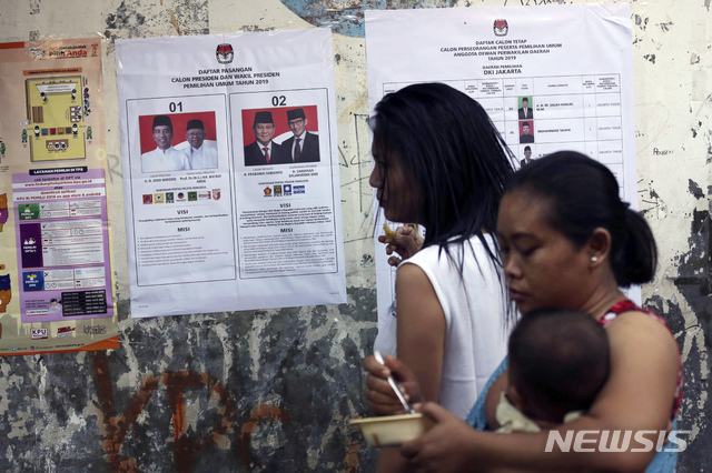인도네시아에서 17일(현지시간) 대통령과 국회의원을 뽑는 선거의 투표가 시작돼 자카르타의 한 투표소에서 유권자들이 대통령 후보 벽보를 살펴보고 있다. / 뉴시스