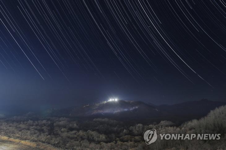 '화해와 평화의 새 길'로 쏟아지는 DMZ의 별강원도 철원군 비무장지대(DMZ)에서 역곡천이 휘감아 도는 이 작은 언덕은 하늘에서 볼 때 화살촉 모양인 까닭에 '화살머리 고지'라 불렸다. 1951년 11월부터 정전협정이 체결된 1953년 7월까지 남북한의 군인뿐만 아니라 미 육군 2사단, 프랑스 대대, 중공군이 치열한 전투를 벌였다. 전사에 따르면 유엔군은 밀려오는 중공군으로부터 고지를 지키기 위해 하루에도 수류탄 수십 상자를 열어야 했다. 던질 겨를도 없이 고지 아래로 수류탄을 계속 굴려 내렸다. 중공군은 유엔군의 식수를 끊기 위해 물가에 전사자 시신을 쌓았고 역곡천은 이내 피와 시신 썩은 물로 가득해졌다. 전쟁은 이곳을 대립과 죽음의 생지옥으로 만들었다.남북은 2018년 9·19 남북군사합의서에 따라 화살머리 고지에 전술도로를 만들었다. 군사적으로 대치 중인 DMZ에서 도로를 연결하는 것은 정전협정이 체결된 이후 65년 만에 처음이다. 이어 내년 4월부터 10월까지 고지 일대에서 공동유해발굴사업을 벌인다. 남북은 대립과 죽음의 격전지에서 함께 유해를 찾으며 화해와 평화의 새로운 길을 시작한다. 사진은 2018년이 저무는 12월 화살머리 고지 전경을 10초 단위로 촬영해 한 화면에 표현한 별의 일주 장면이다. 고지 허리를 가르는 전술도로에 눈이 쌓여 있다. 2018.12.30 / 연합뉴스