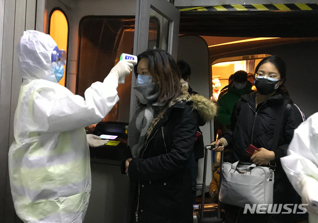 보호복을 입은 보건 관계자들이 22일 중국 베이징 공항에서 우한시에서 도착한 승객들의 체온을 체크하고 있다. 중국은 신종 코로나바이러스로 발생하는 우한 폐렴의 확산을 막기 위해 23일부터 모든 항공기와 열차들의 우한 출발을 막기 시작했다. 2020.1.23 / 뉴시스