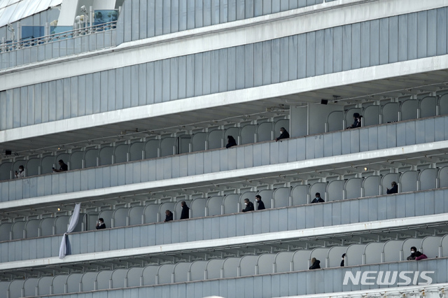 지난 19일 일본 요코하마항에 정박 격리중인 크루즈선 다이아몬드 프린세스호에서 일부 승객들이 발코니에 나와 밖을 바라보고 있다. 2020. 2. 19. / 뉴시스