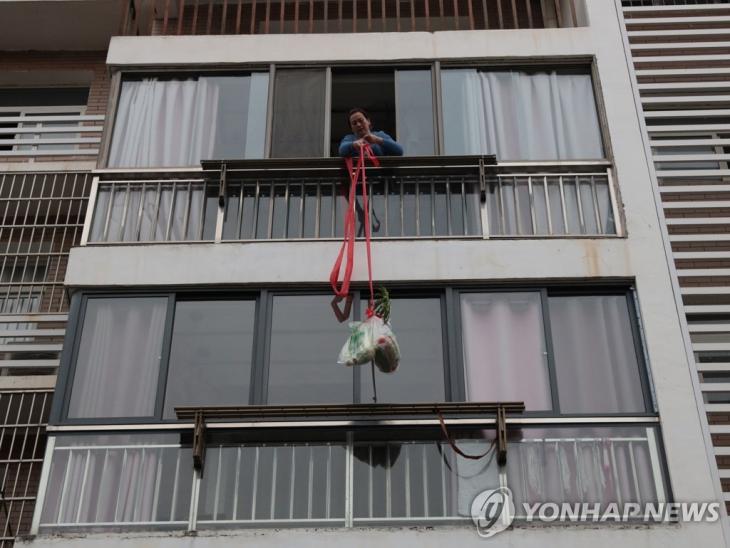 로프 이용 식품 배급받는 후베이성 주민. 신종 코로나바이러스 감염증(코로나19) 예방책으로 출입이 통제된 중국 후베이 이창의 한 주거단지에서 22일 입주민이 로프를 이용해 지역 공무원들이 전달한 식품을 끌어올리고 있다. / 연합뉴스