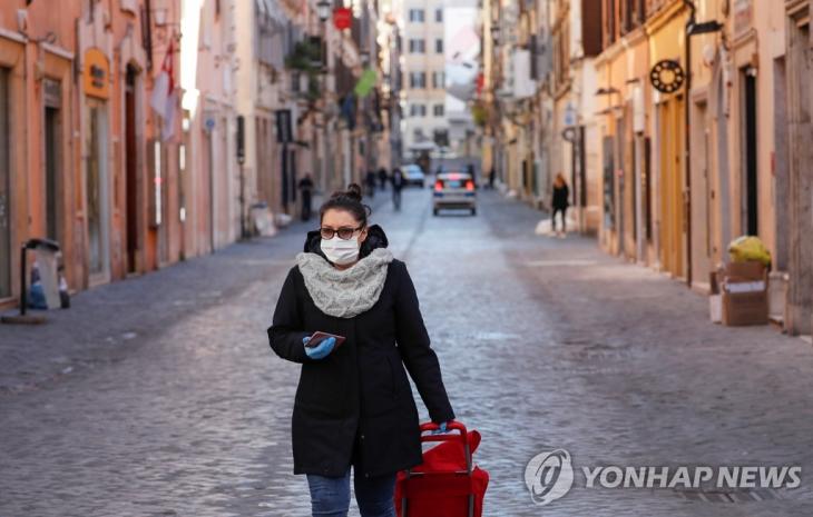 '전국 이동제한령' 이탈리아 로마의 한산한 거리. 신종 코로나바이러스 감염증(코로나19)이 무서운 속도로 확산하는 이탈리아에서 전례 없는 전국 이동제한령이 발효된 지 사흘째를 맞은 12일(현지시간) 로마에서 한 여성이 마스크를 쓴 채 거의 인적이 끊긴 거리를 지나가고 있다. / 연합뉴스