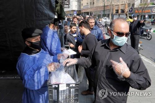 이란 준군사조직 바시즈 민병대가 무료 배포하는 위생용품 세트를 받는 테헤란 시민 [AP=연합뉴스]