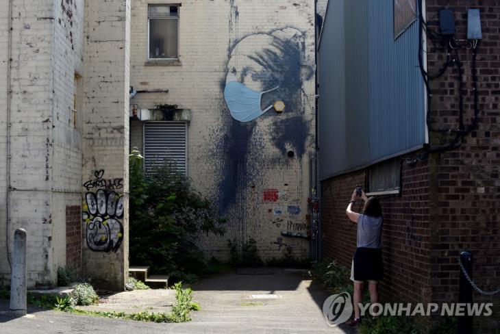 마스크가 새로 덧씌워진 뱅크시의 벽화 '피어싱을 한 소녀' [로이터=연합뉴스]