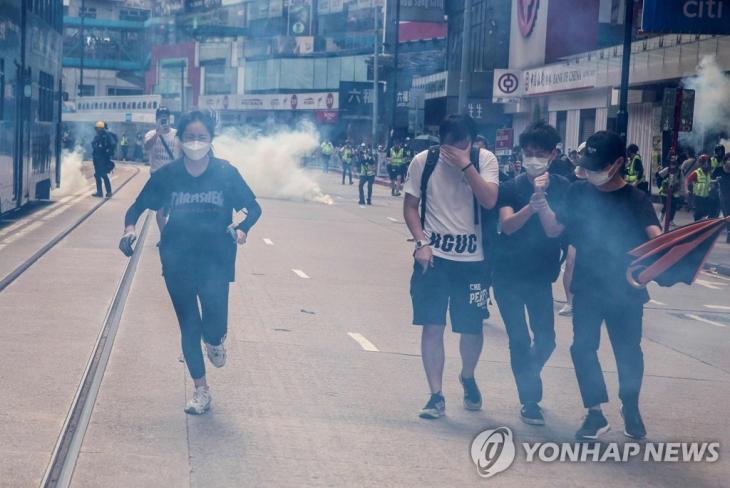 경찰 최루가스 발사에 피신하는 홍콩 시위대. 중국 전국인민대표대회(전인대)의 '홍콩 국가보안법'(홍콩보안법) 제정 추진에 반발한 홍콩 시민들이 24일 거리에서 시위를 벌이다 경찰이 최루가스를 쏘자 달아나고 있다. / 연합뉴스