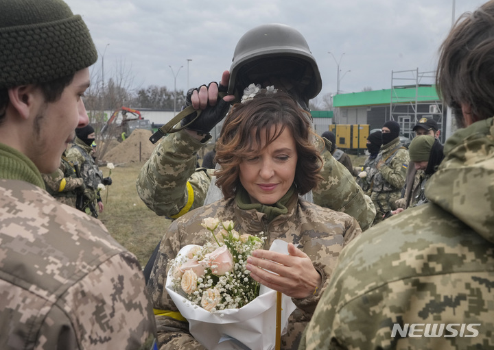 6일(현지시간) 우크라이나 키이우의 한 검문소에서 우크라이나 국토방위군 대원 한 쌍의 결혼식이 열려 신부가 꽃다발과 촛불을 들고 있다. 2022.03.07. / 뉴시스
