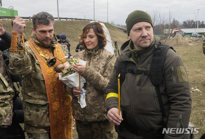 6일(현지시간) 우크라이나 키이우의 한 검문소에서 군목의 인도로 우크라이나 국토방위군 대원 한 쌍의 결혼식이 열리고 있다.  2022.03.07. / 뉴시스