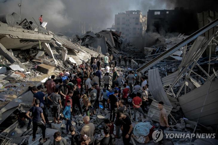 (가자지구 AFP=연합뉴스) 26일(현지시간) 팔레스타인 가자지구에서 주민들이 이스라엘 공습으로 파괴된 건물 주위에 모여있다. 지난 7일 팔레스타인 무장 정파 하마스가 이스라엘을 공격해 교전이 벌어진 뒤 양측에서 7천 명 이상이 사망했다. 2023.10.27